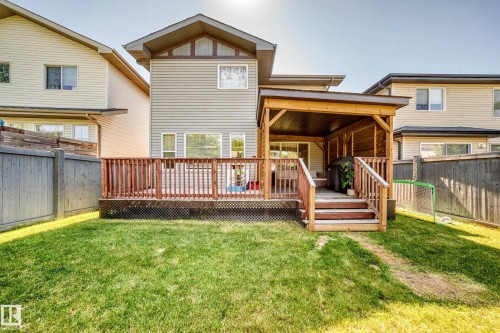 Expansive backyard with a covered wooden deck, privacy fencing, and a manicured lawn - 3433 Goodridge Link Link, Edmonton, AB 