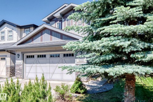 Exterior featuring a double garage with decorative paneling and upper window inserts - 3433 Goodridge Link Link, Edmonton, AB 