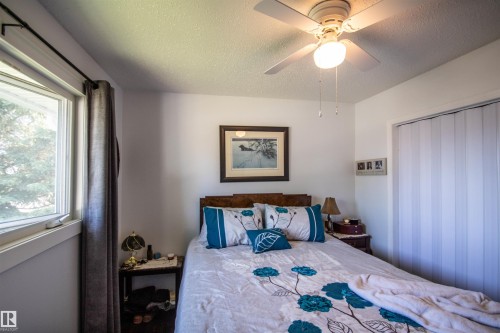 Room featuring a window, built-in ceiling fan with light, and a closet with a bi-fold door - 5217 47 Ave, St. Paul Town, AB 