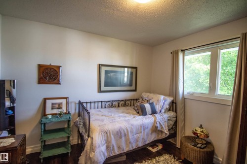 Bright interior room featuring a large window, dark wood-finish flooring, and white walls - 5217 47 Ave, St. Paul Town, AB 