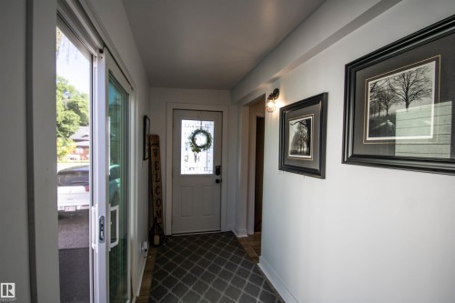 Entryway featuring a white paneled door with decorative glass, a sliding glass door, white walls, and a patterned floor covering - 5217 47 Ave, St. Paul Town, AB 