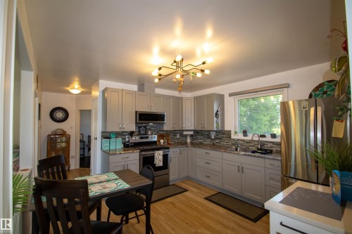 Updated kitchen featuring light gray cabinetry, granite-style countertops, and a mosaic tile backsplash - 5217 47 Ave, St. Paul Town, AB 