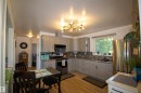 Updated kitchen featuring light gray cabinetry, granite-style countertops, and a mosaic tile backsplash - 5217 47 Ave, St. Paul Town, AB 