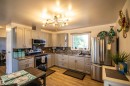 Kitchen featuring light gray cabinetry, stainless steel appliances, granite-style countertops, and a full tile backsplash - 5217 47 Ave, St. Paul Town, AB 