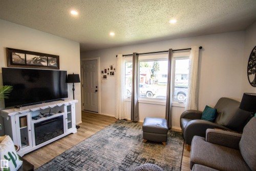 Living area featuring wood-finish flooring, recessed lighting, white walls, and multiple windows - 5217 47 Ave, St. Paul Town, AB 