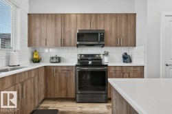 Kitchen featuring wood-finish cabinetry, white countertops, subway tile backsplash, and a black appliance suite - 