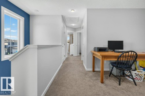 Upper-level hallway featuring a window with grid pattern, carpeted flooring, and light gray wall paint - 2116 Maple Road, Edmonton, AB 