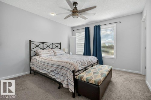 Carpeted bedroom with a ceiling fan, recessed lighting, and two windows featuring blinds and drapery - 2116 Maple Road, Edmonton, AB 