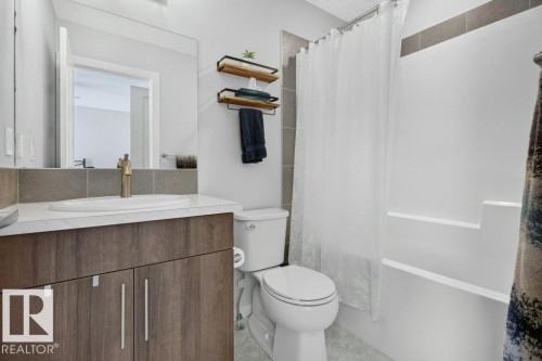 Contemporary bathroom featuring a white single-sink vanity with wood-finish cabinetry and a bronze-finish faucet - 2116 Maple Road, Edmonton, AB 