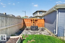 Paved patio area featuring a wooden privacy fence, a raised garden bed, and a grass lawn - 