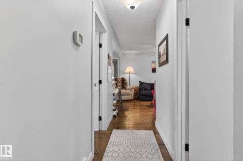 Hallway with wood-finish flooring, white baseboards, and a flush-mount ceiling light fixture - 9821 153 Street, Edmonton, AB - Indoor Photo Showing Other Room