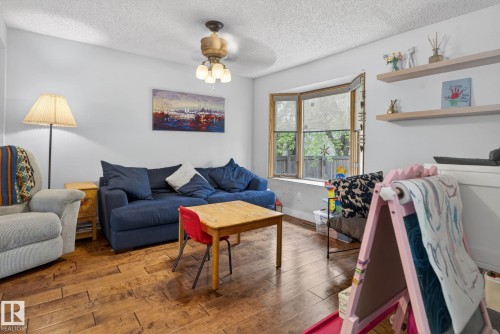 Living area featuring wood-finish flooring, a bay window with multiple panes, and white walls - 9821 153 Street, Edmonton, AB - Indoor Photo Showing Living Room
