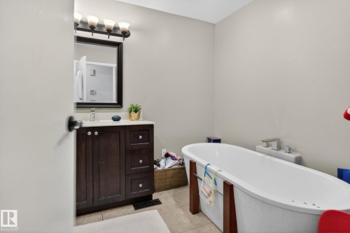Bathroom featuring a freestanding oval tub and a dark wood-finish vanity with a white countertop - 9821 153 Street, Edmonton, AB - Indoor Photo Showing Bathroom