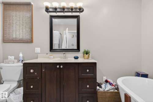 Bathroom vanity featuring a light-toned countertop, undermount sink, and dark wood-finish cabinetry with drawers - 9821 153 Street, Edmonton, AB - Indoor Photo Showing Bathroom