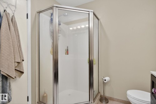 Corner glass shower enclosure with a white base and silver-tone framing - 9821 153 Street, Edmonton, AB - Indoor Photo Showing Bathroom