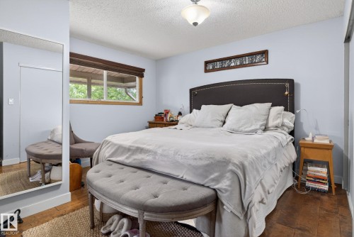 Bedroom featuring wood-finish flooring, light blue painted walls, and a window with a wood frame - 9821 153 Street, Edmonton, AB - Indoor Photo Showing Bedroom