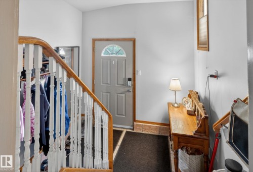 Entryway featuring a grey paneled door with an arched transom window, wood-finish flooring, and a staircase with white spindles and a natural wood handrail - 9821 153 Street, Edmonton, AB - Indoor Photo Showing Other Room