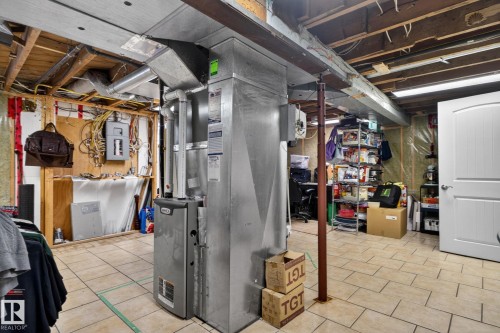 Utility room featuring a furnace, exposed ceiling joists, and tile flooring - 9821 153 Street, Edmonton, AB - Indoor Photo Showing Basement