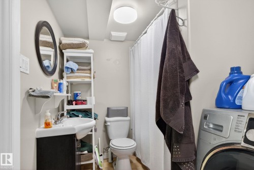 Full bathroom featuring a dark wood-finish vanity with an integrated sink, a white shower curtain, and a white toilet - 9821 153 Street, Edmonton, AB - Indoor Photo Showing Laundry Room
