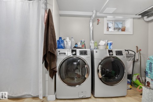 Dedicated laundry area featuring a front-loading washer and dryer set, neutral wall color, and a small window for natural illumination - 9821 153 Street, Edmonton, AB - Indoor Photo Showing Laundry Room