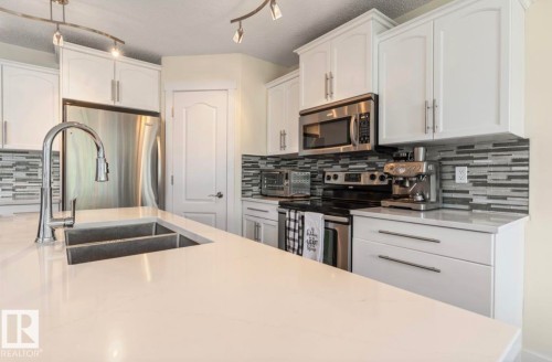 Kitchen island with a double basin sink and gooseneck faucet - 1007 Macewan Cl, Edmonton, AB 