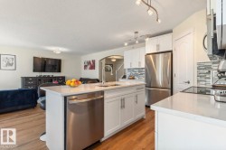 Contemporary kitchen featuring white cabinetry, light countertops, and stainless steel appliances - 