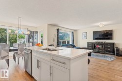 Kitchen island featuring a double-basin sink, stainless steel faucet, and white cabinetry with brushed nickel hardware - 