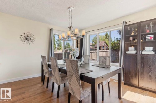 Inviting dining space featuring wood-finish flooring, a contemporary chandelier, and expansive windows - 1007 Macewan Cl, Edmonton, AB 