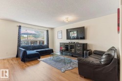 Spacious living area featuring wood-finish flooring, a large picture window, and a ceiling-mounted light fixture - 