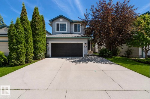 Two-story residence featuring light gray siding, dark garage door, and a concrete driveway - 1007 Macewan Cl, Edmonton, AB 