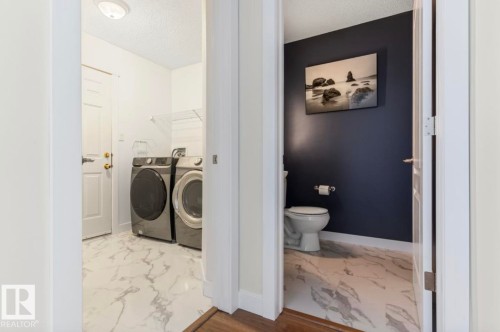 Dedicated laundry area featuring a full-size washer and dryer, complemented by marble-look tile flooring - 1007 Macewan Cl, Edmonton, AB 