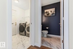 Dedicated laundry area featuring a full-size washer and dryer, complemented by marble-look tile flooring - 