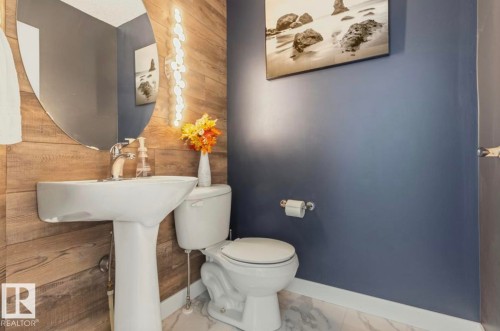 Pedestal sink with chrome faucet, oval mirror, and vertical accent lighting - 1007 Macewan Cl, Edmonton, AB 