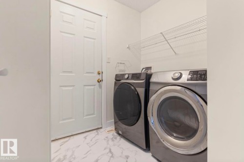 Dedicated laundry area featuring a white six-panel door, white walls, and wire shelving - 1007 Macewan Cl, Edmonton, AB 