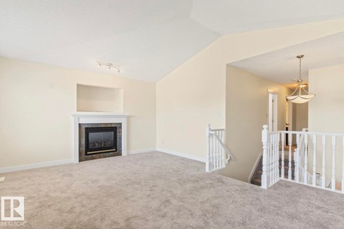 Living area with a fireplace featuring a dark tile surround and white mantel - 1007 Macewan Cl, Edmonton, AB 