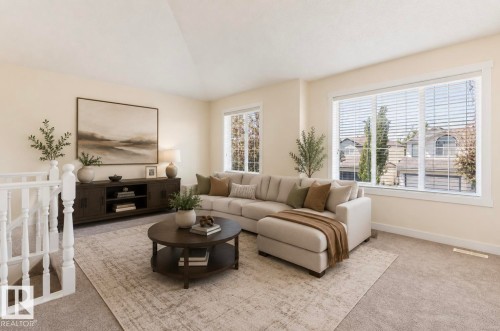 Spacious living area featuring light-toned walls, neutral carpeting, and multiple windows - 1007 Macewan Cl, Edmonton, AB 