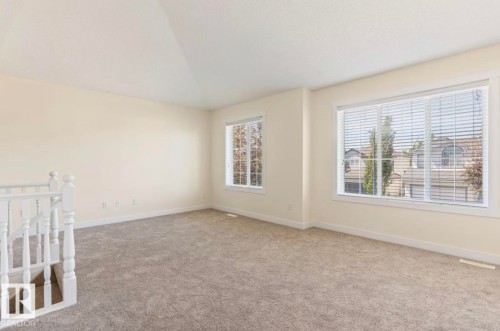 Vaulted ceiling room featuring neutral-toned carpeting, light-toned wall paint, white trim, and white window blinds - 1007 Macewan Cl, Edmonton, AB 