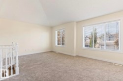 Vaulted ceiling room featuring neutral-toned carpeting, light-toned wall paint, white trim, and white window blinds - 