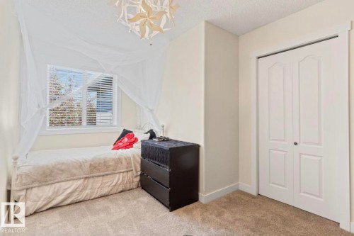 Plush carpeting provides comfort in this room featuring a window with blinds, white trim, and a bi-fold closet door - 1007 Macewan Cl, Edmonton, AB 