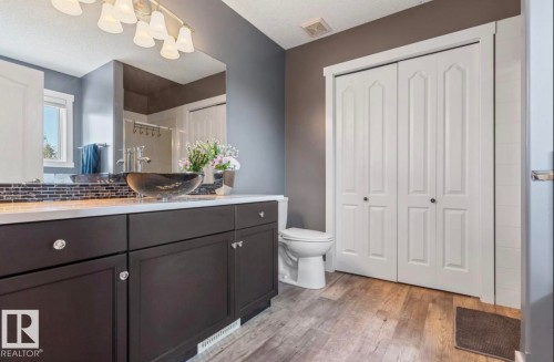 Vanity featuring a vessel sink, dark wood-finish cabinetry, and a light-colored countertop - 1007 Macewan Cl, Edmonton, AB 