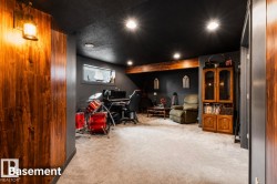 Finished basement featuring wood-finish accent walls, recessed lighting, and a neutral carpeted floor - 