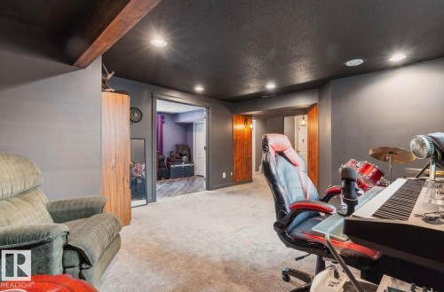 Carpeted area with recessed lighting, dark painted walls, and an exposed wood ceiling beam - 1007 Macewan Cl, Edmonton, AB 