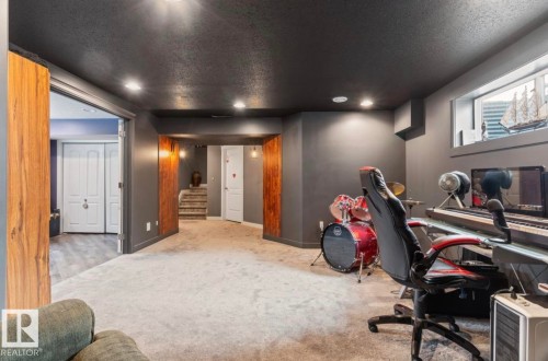 Spacious lower-level room featuring light-toned carpeting and dark gray walls - 1007 Macewan Cl, Edmonton, AB 