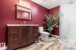 Bathroom featuring a dark wood-finish vanity with a white countertop, a framed mirror, and a curved glass shower enclosure - 