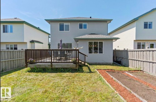 Expansive backyard featuring a wood deck, manicured lawn, and raised garden beds - 1007 Macewan Cl, Edmonton, AB 