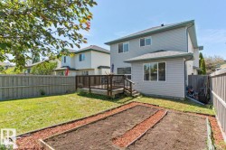 Spacious backyard featuring a wooden privacy fence, a large elevated deck with railings, and two distinct garden beds - 