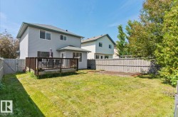 Expansive backyard featuring a wood deck with dark railing, a privacy fence, and a designated garden bed - 