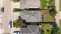 Single-story residence with a gray shingle roof, featuring a paved driveway and a spacious backyard - 