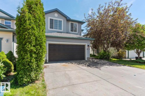 Two-story residence featuring light gray siding, a dark gray garage door, and a concrete driveway - 1007 Macewan Cl, Edmonton, AB 