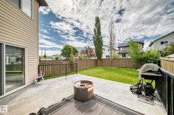 Rear exterior featuring a concrete patio, sliding glass door, and a fenced yard with a manicured lawn - 